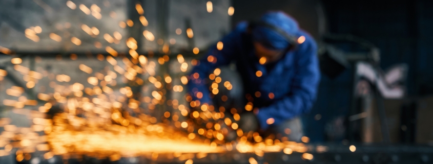 Worker doing gate by electric steel cutter machine.